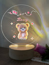 a light up teddy bear on a wooden base