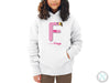 a young girl wearing a white hoodie with the letter f on it