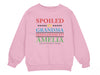 a young girl wearing a pink sweatshirt with the words spoiled by grandma and loving by